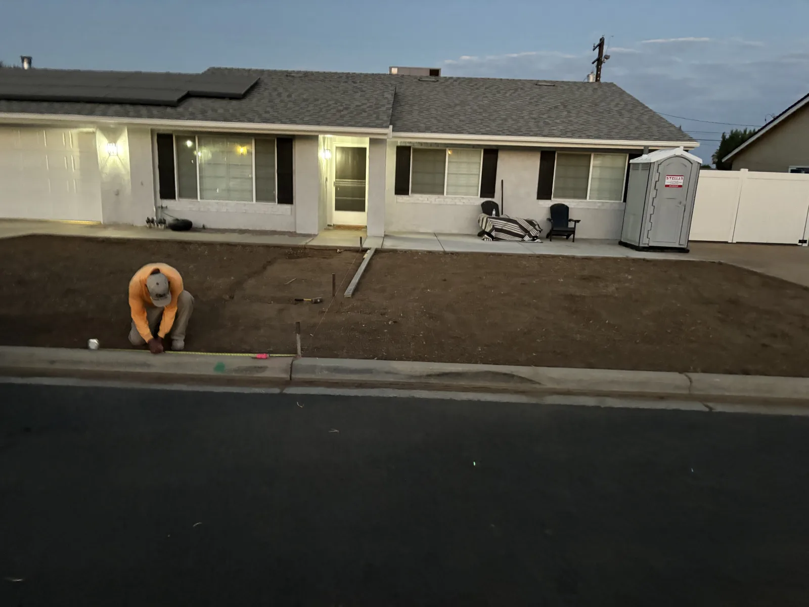 Front yard with bare soil and a worker preparing the ground