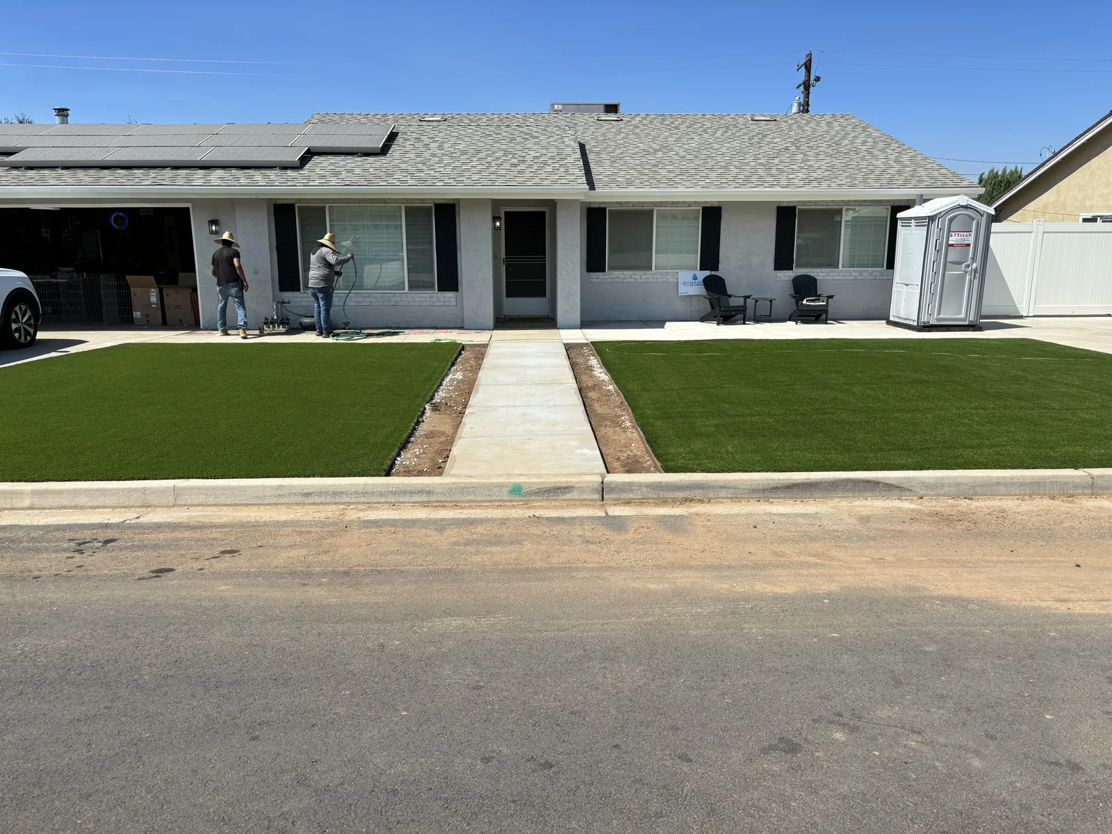 Wide view of green front yard areas and a central walkway leading to the home
