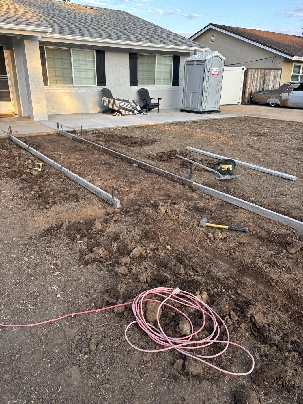 Front yard under preparation with a central path layout and exposed pipework